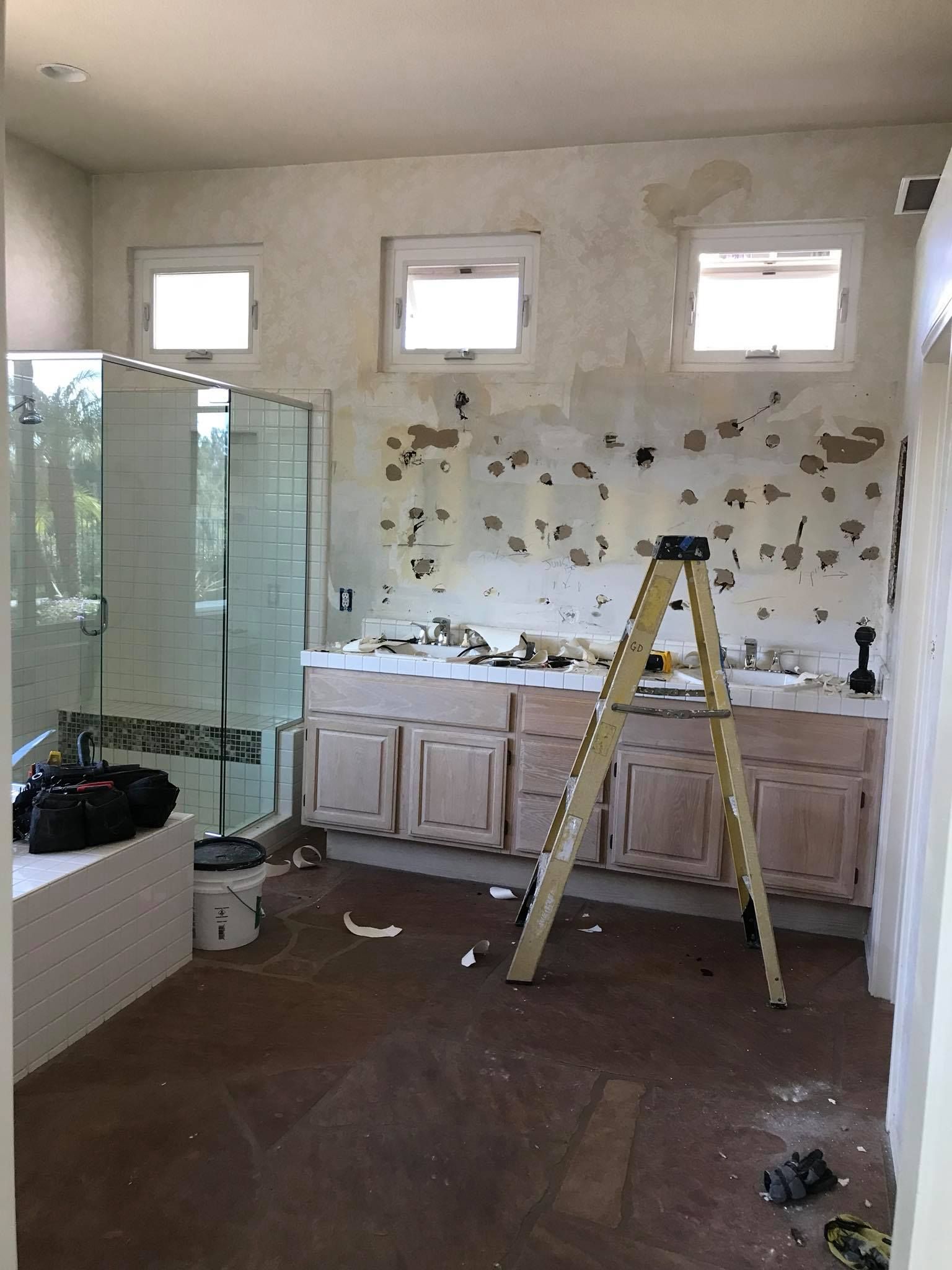 A bathroom under construction with a ladder in the middle of the room.