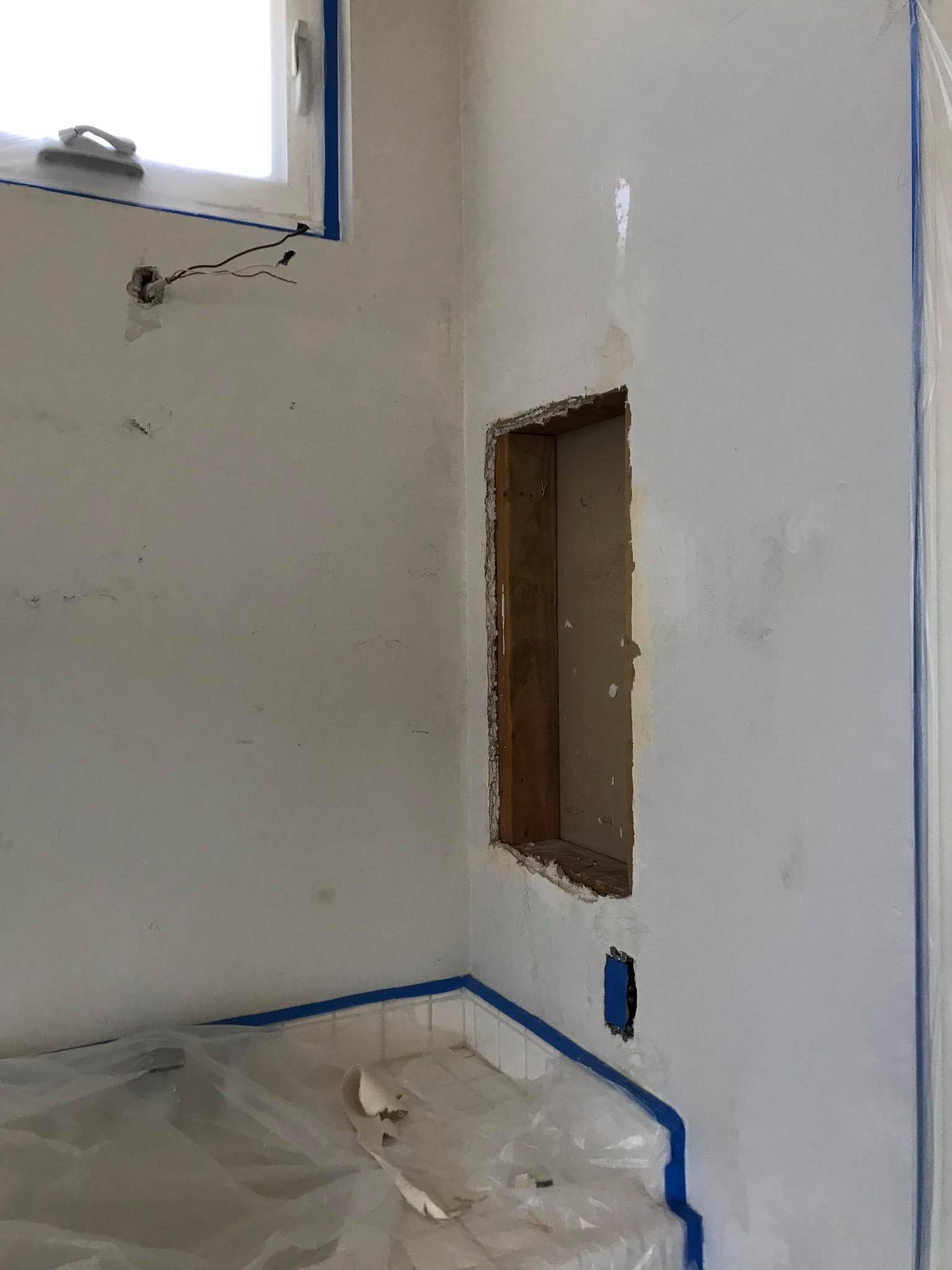 A bathroom with a hole in the wall and a window.