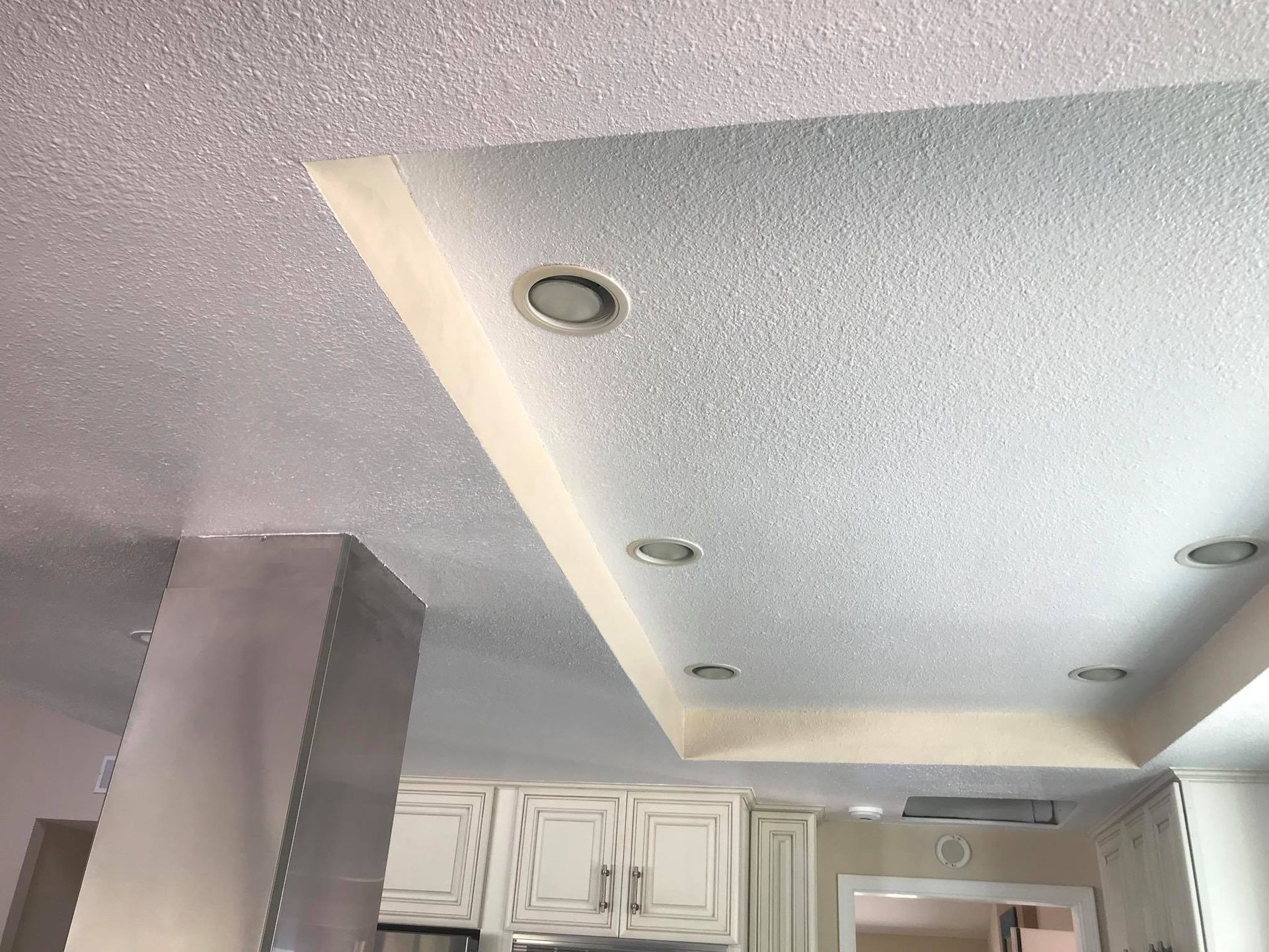 A kitchen with white cabinets and a white ceiling.