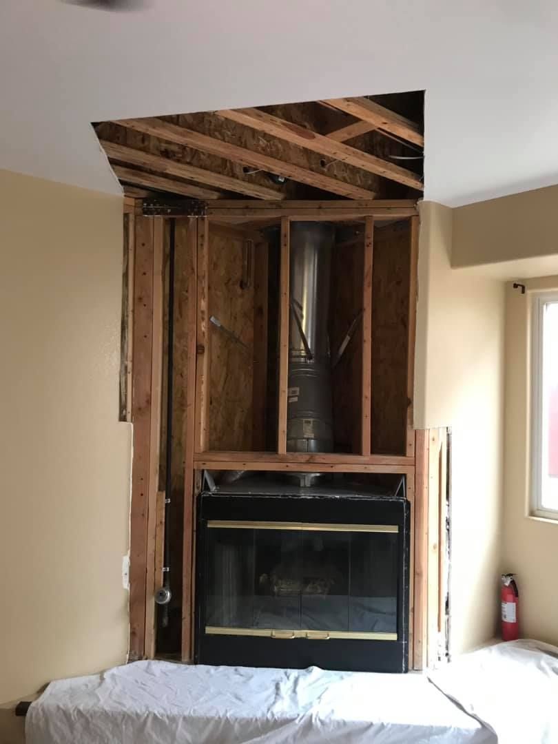 A fireplace is being built in a room with a hole in the ceiling.