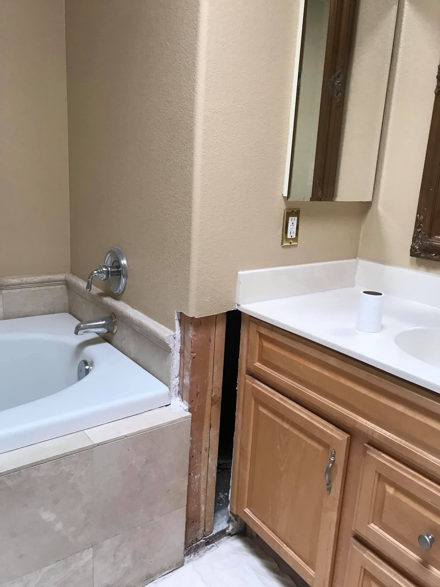 A bathroom with a tub , sink and mirror.
