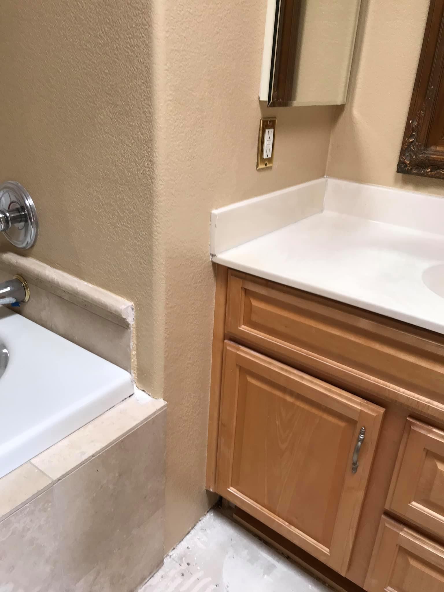 A bathroom with a bathtub , sink and mirror.