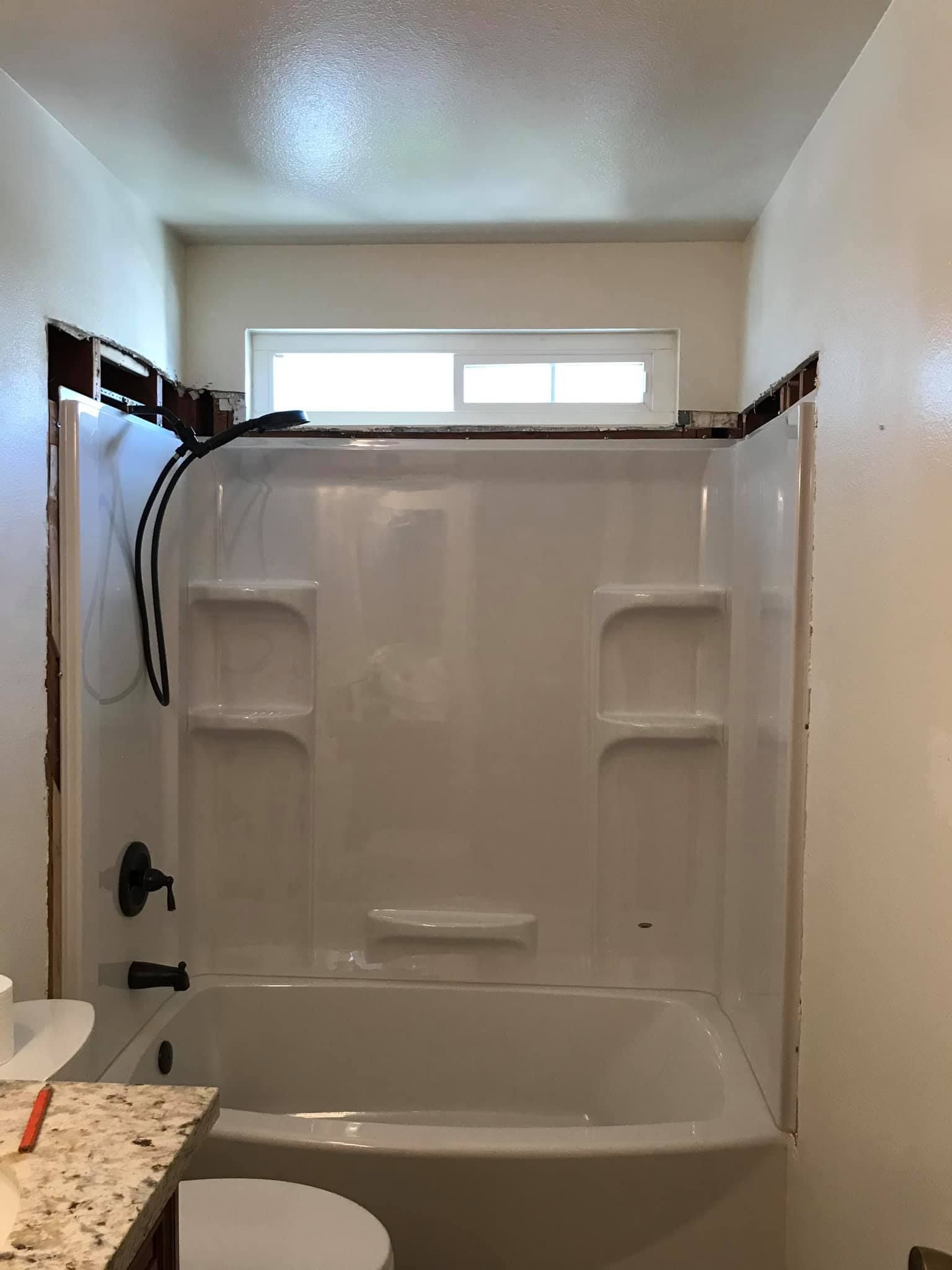 A bathroom with a bathtub , toilet , and window.