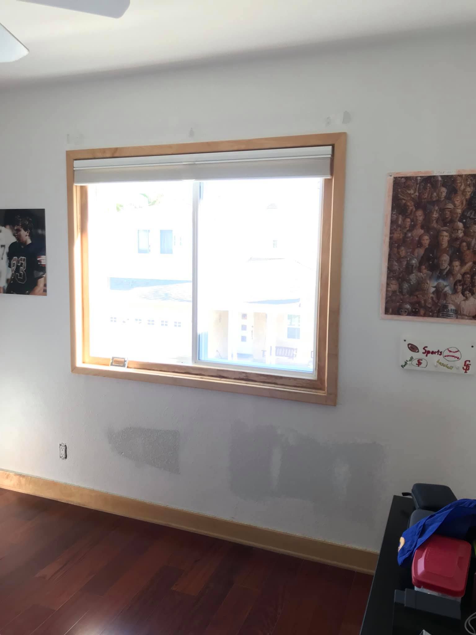 A room with a large window and a picture on the wall