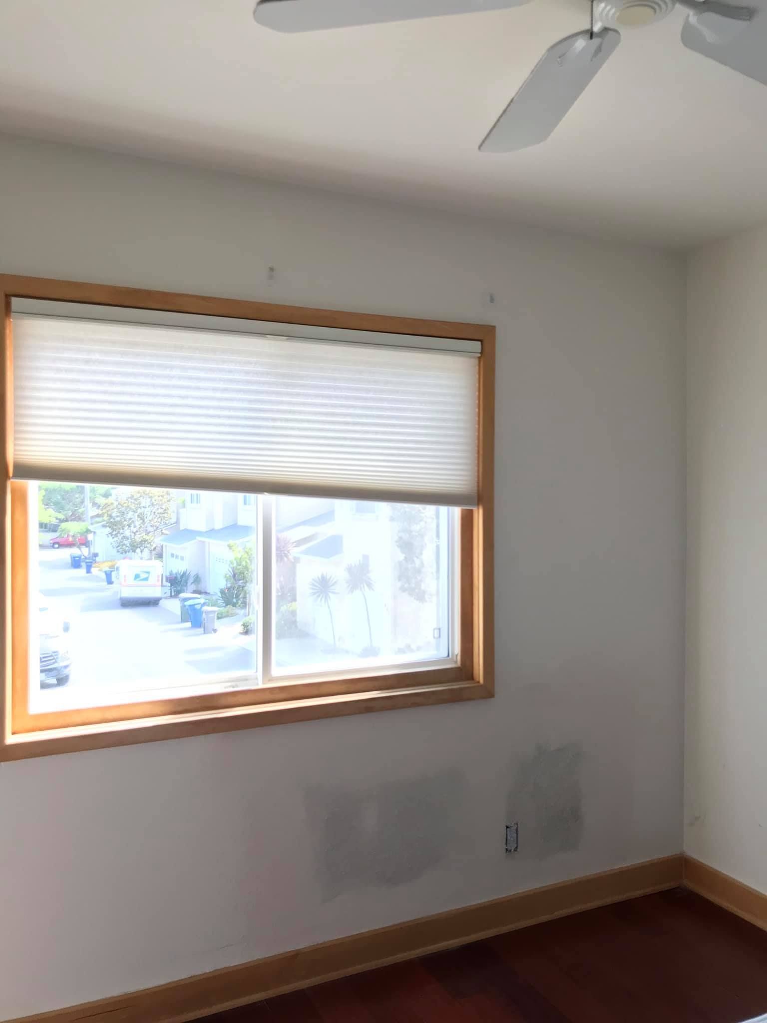 A bedroom with a large window and a ceiling fan