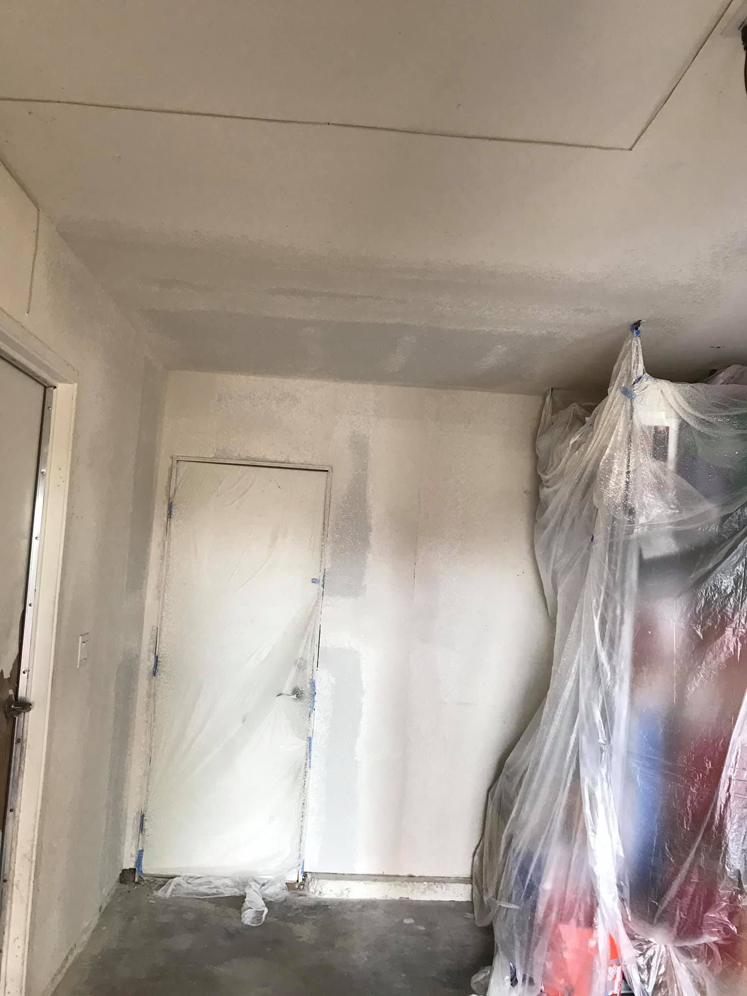 A room with a ceiling and a door covered in plastic.