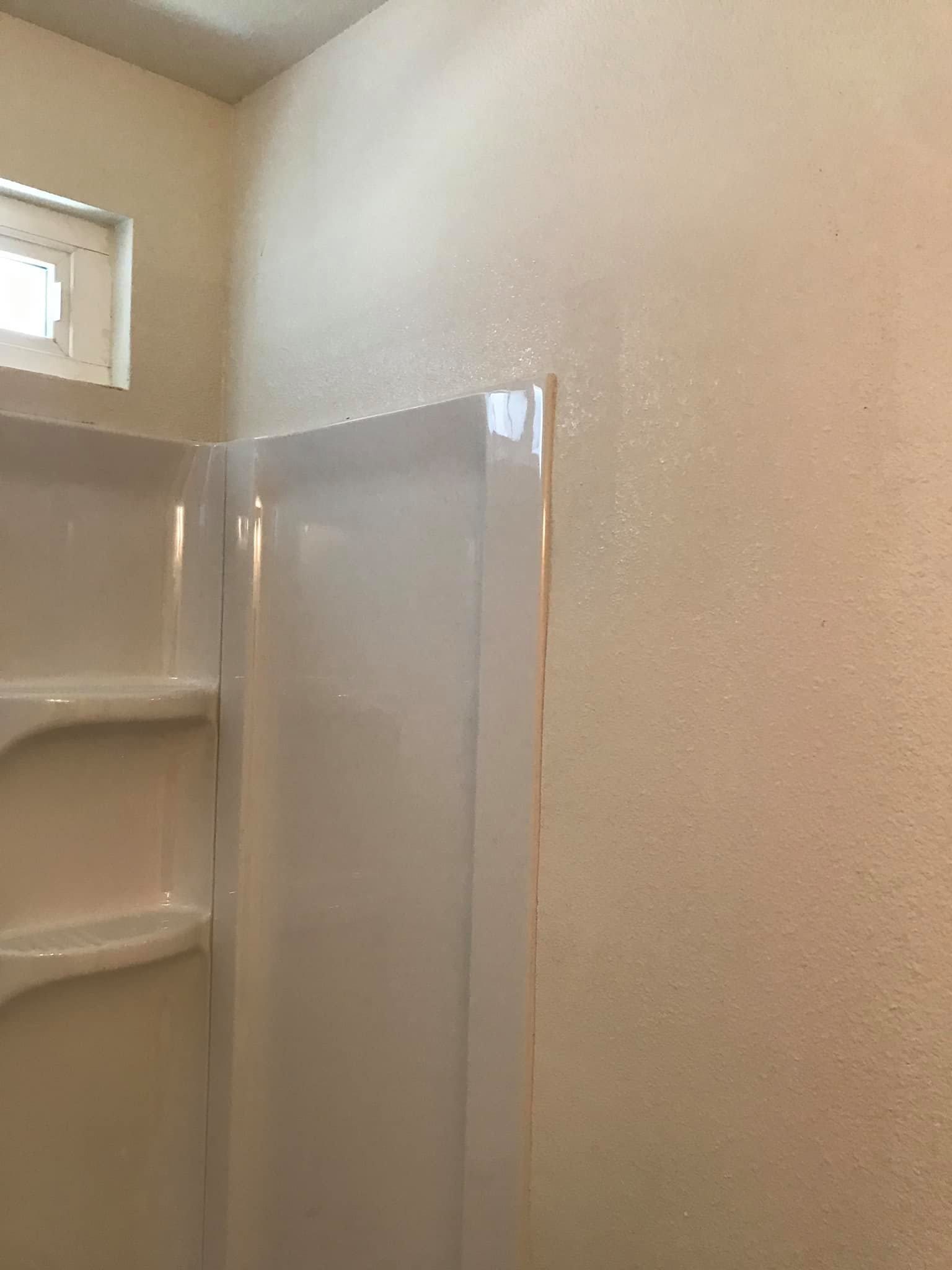 A bathroom with a shower stall and a window.