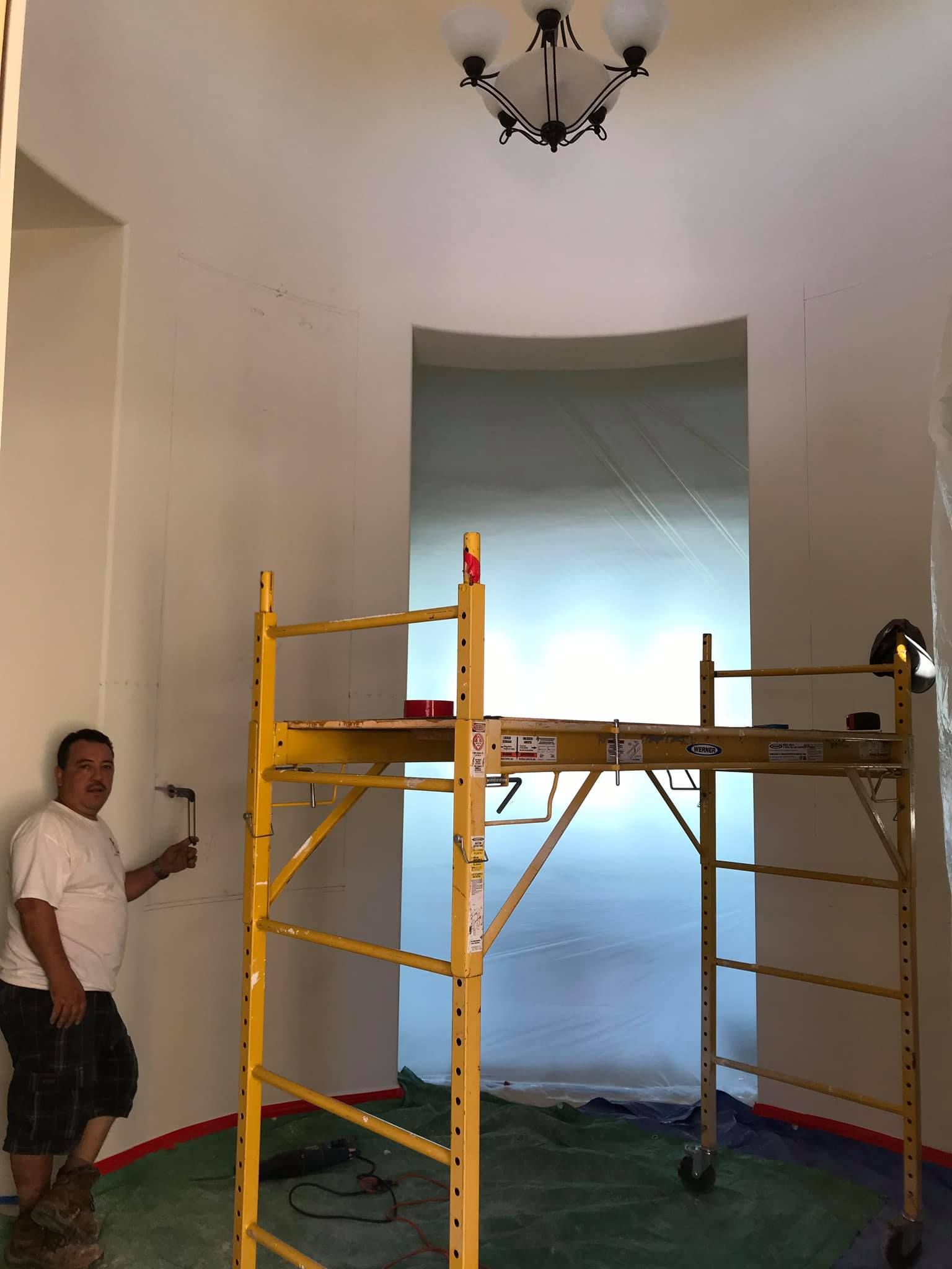 A man is standing next to a yellow scaffolding in a room.