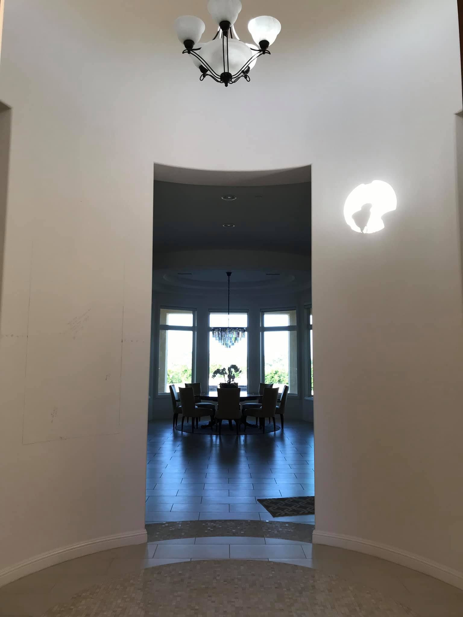 A hallway leading to a dining room with a chandelier hanging from the ceiling
