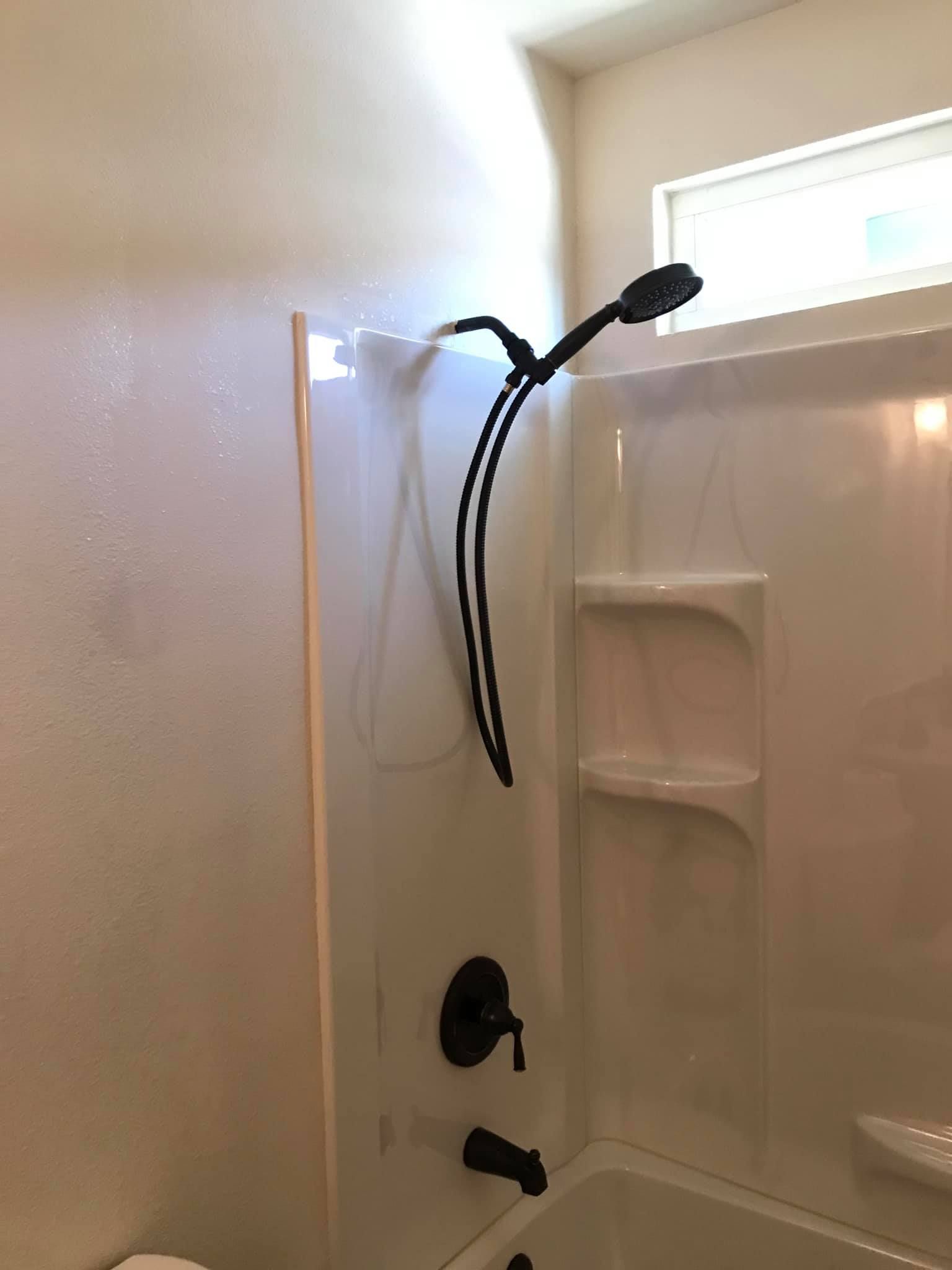 A bathroom with a tub , shower , toilet and window.