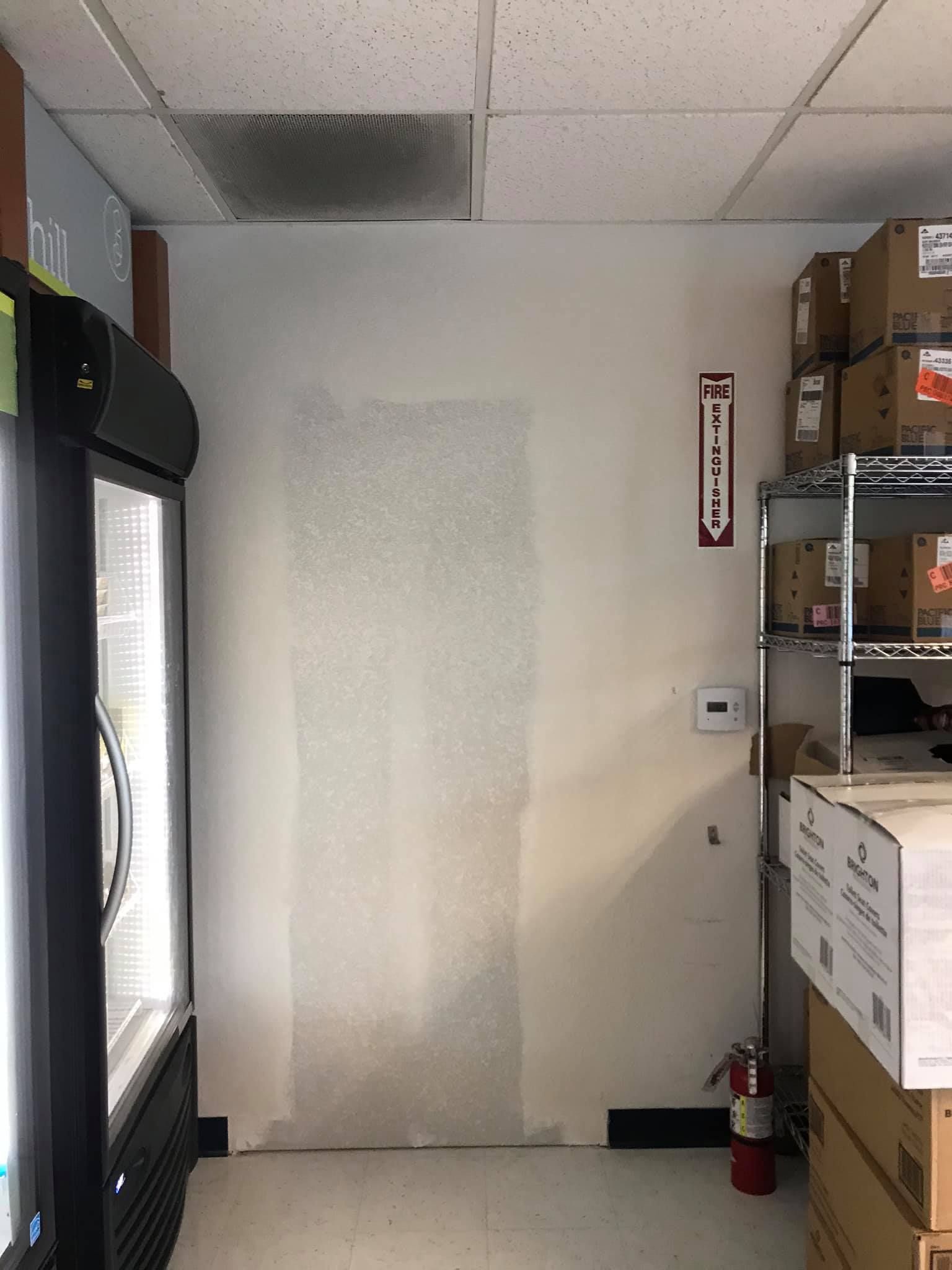 A room with a refrigerator and a fire extinguisher in it.