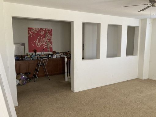 A living room with white walls and a ceiling fan