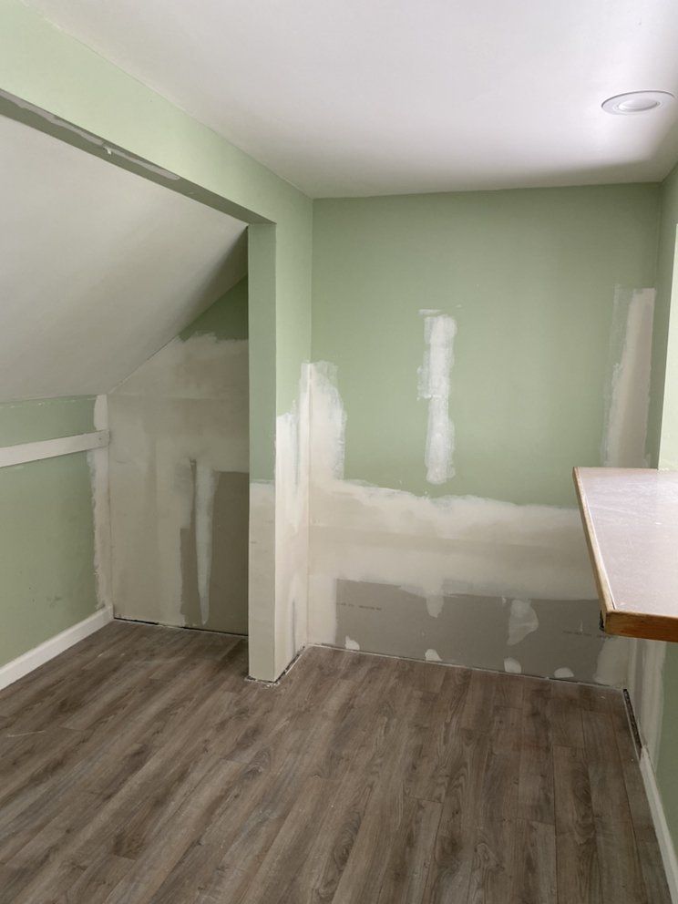 An empty room with green walls and a wooden floor.
