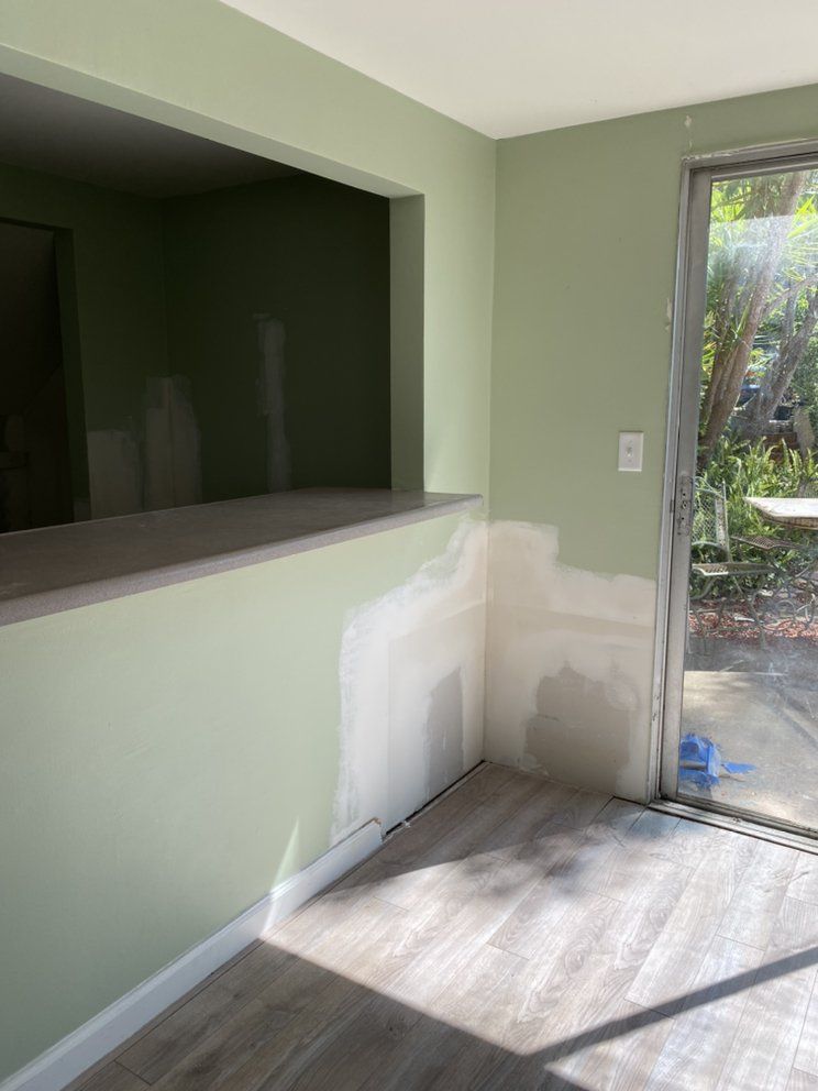 An empty room with green walls and a sliding glass door.