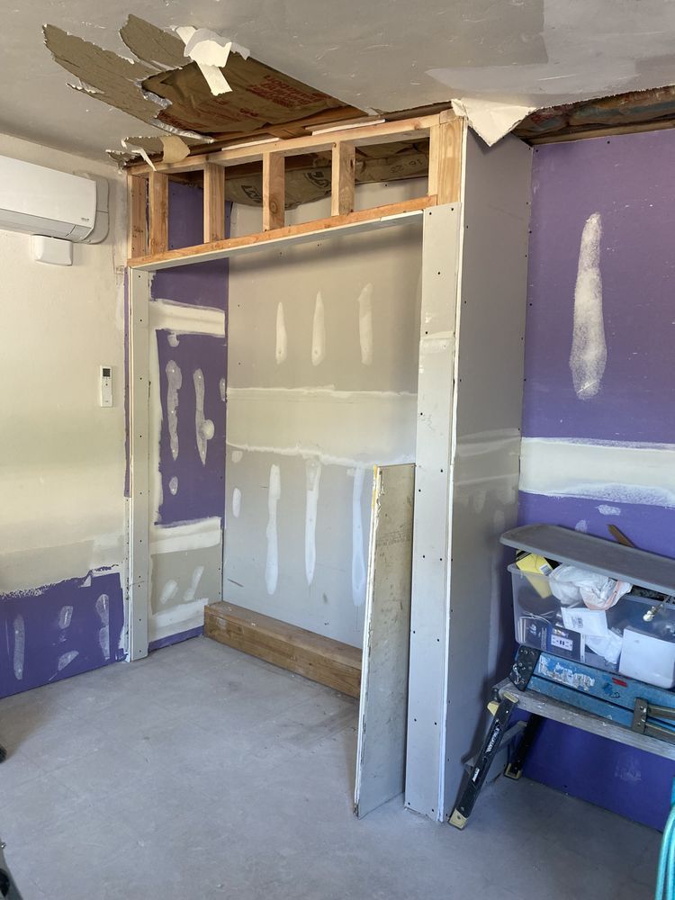 A room with purple walls and a ladder in it is being remodeled.