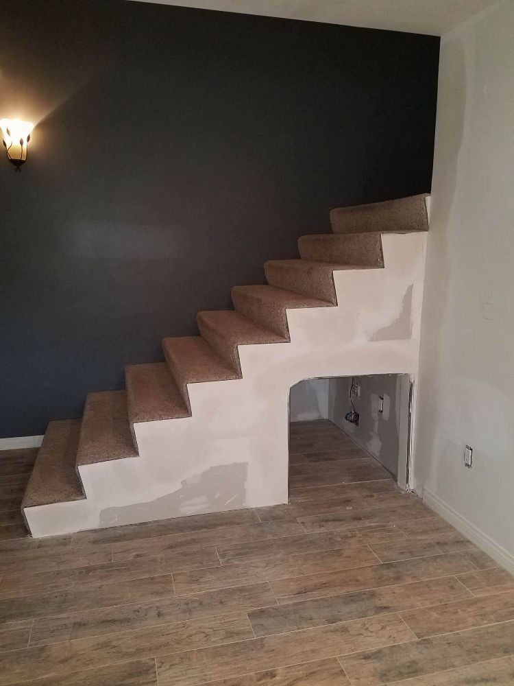 A staircase in a room with a wooden floor and a black wall.