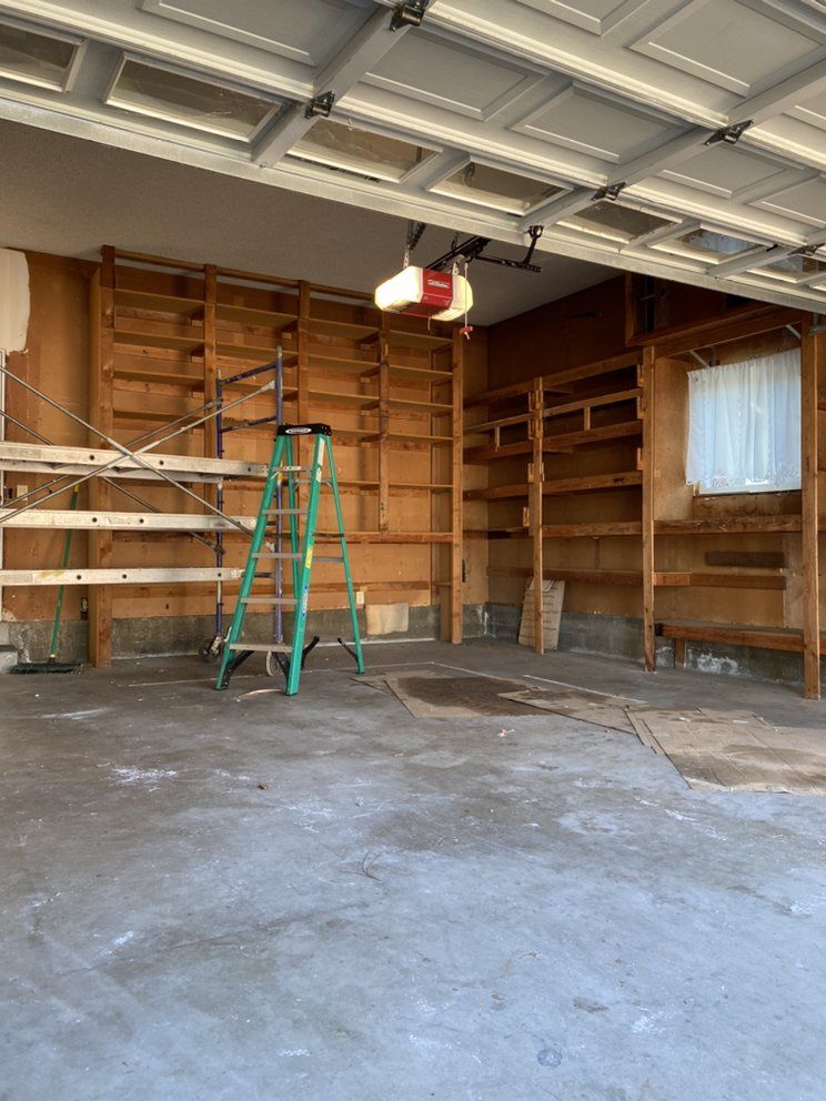 An empty garage with a ladder in the middle of it