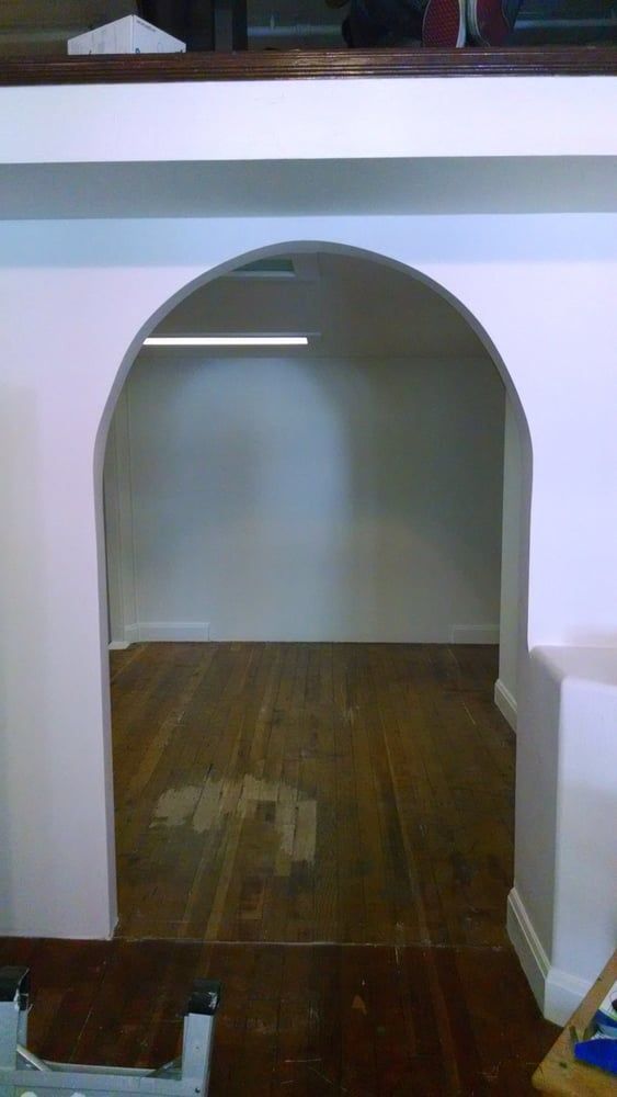 A white archway in a room with a wooden floor.