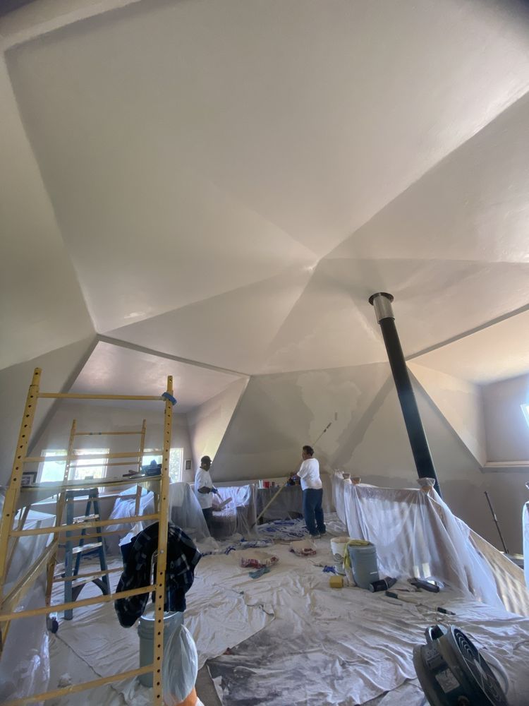A group of people are painting the ceiling of a building.