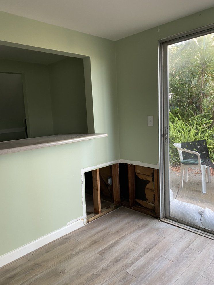 A living room with a sliding glass door and a hole in the wall.