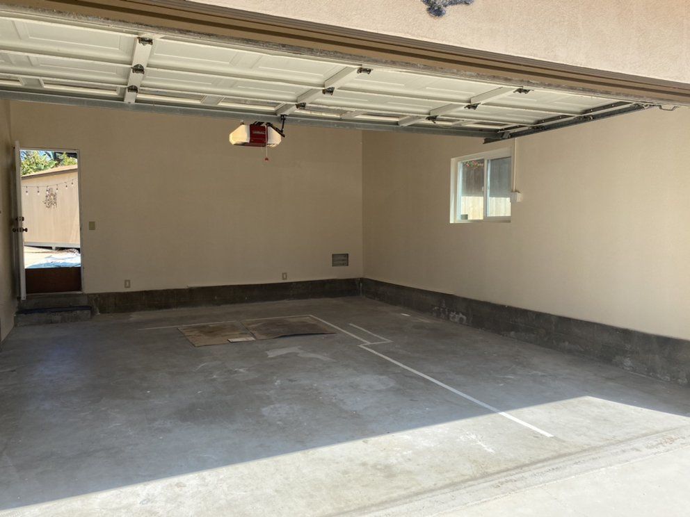 An empty garage with a garage door open and a window.