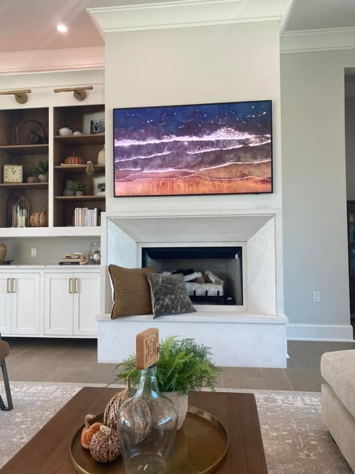 Wall-mounted TV showing a landscape wallpaper above a console with game consoles and decor