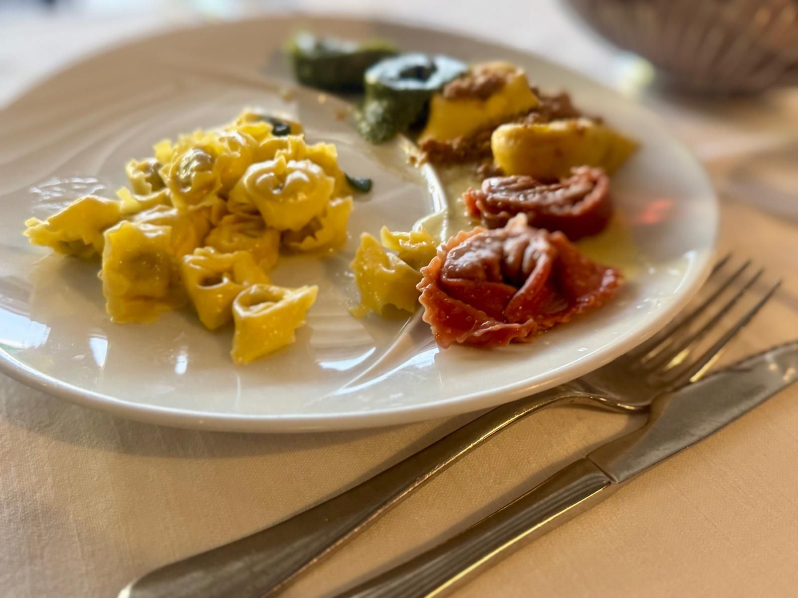 Bunte gefüllte Nudeln auf einem weißen Teller mit Besteck, serviert in einem Restaurant.