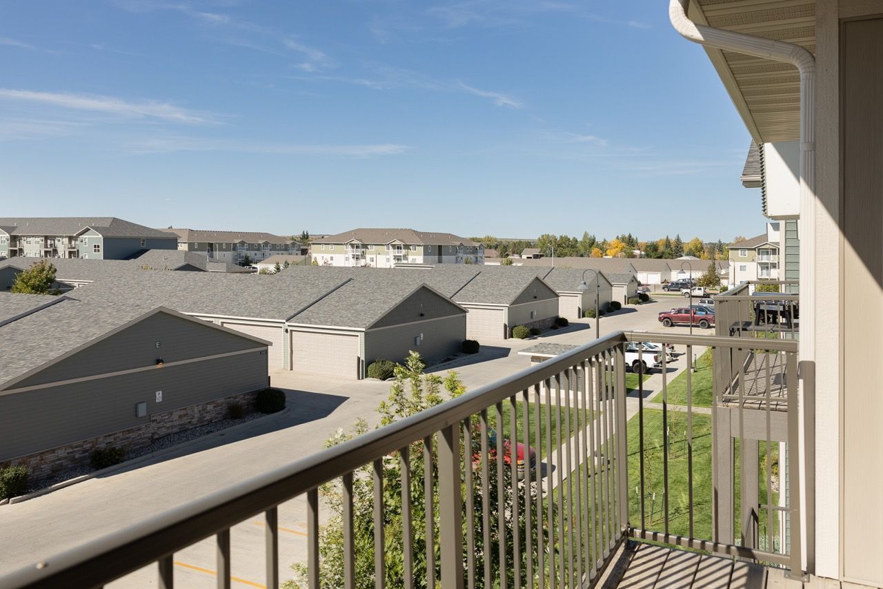 Balcony view of a multi-building apartment community with garages and parking.