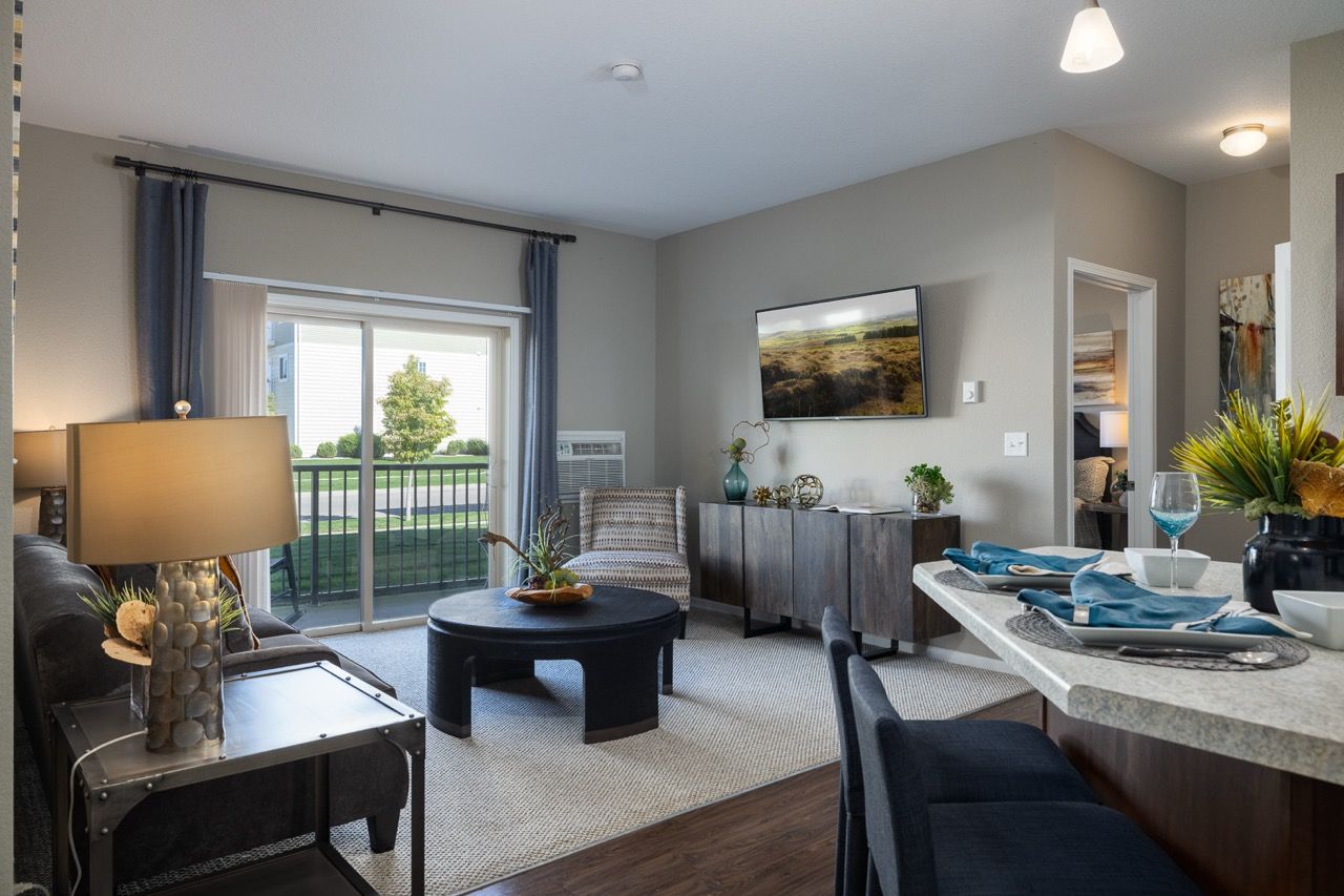 Living room in an apartment with sofa, coffee table, TV, and sliding balcony door.