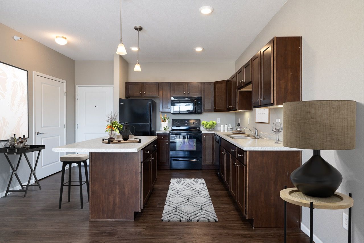 Modern apartment kitchen with dark wood cabinets, island, and stainless steel appliances.