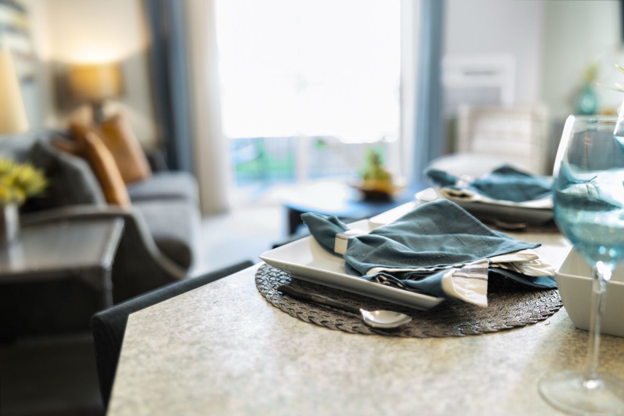 Dining table with blue napkins, plates, and glassware in a modern living area.