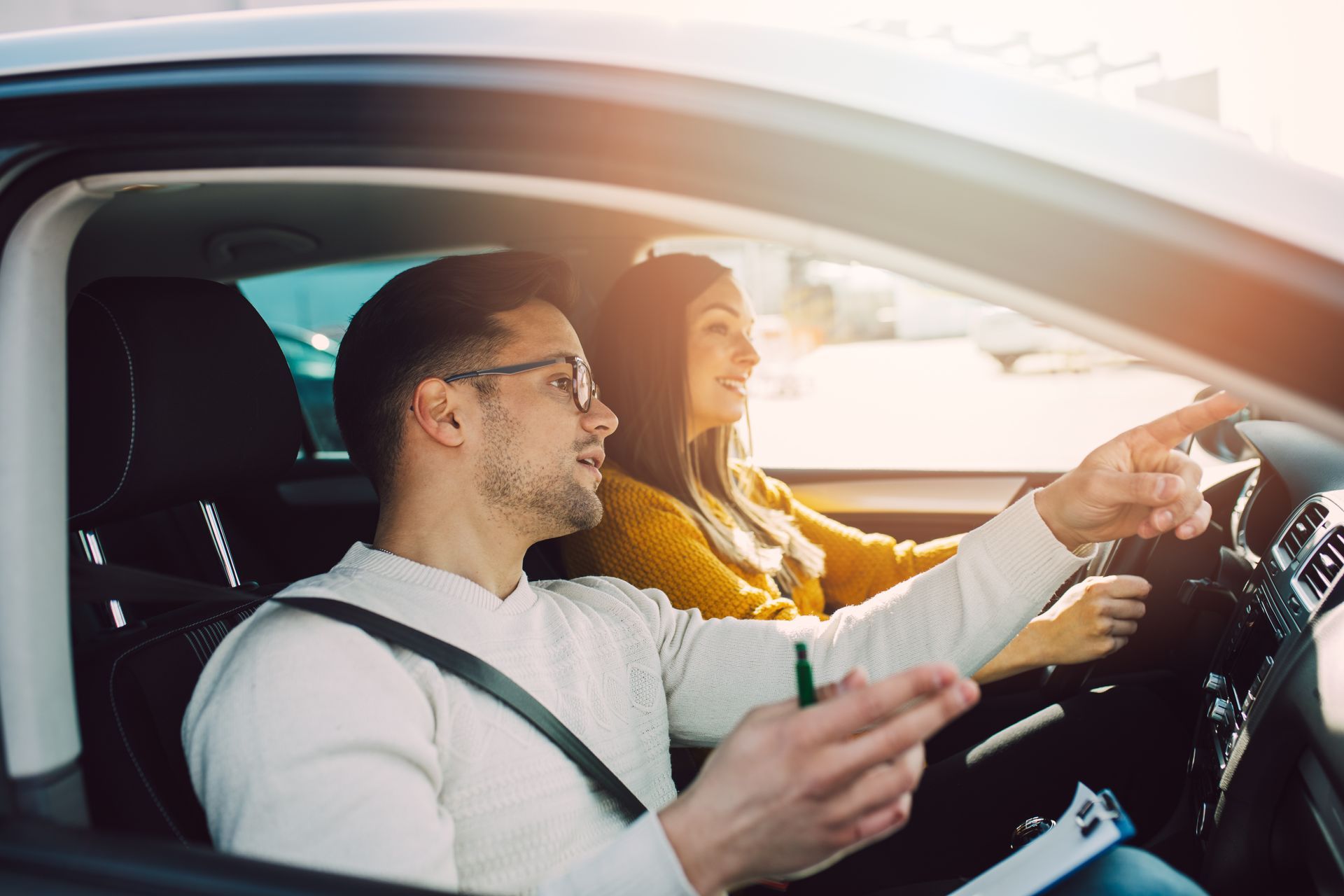 A woman is learning how to drive a car with her instructor.