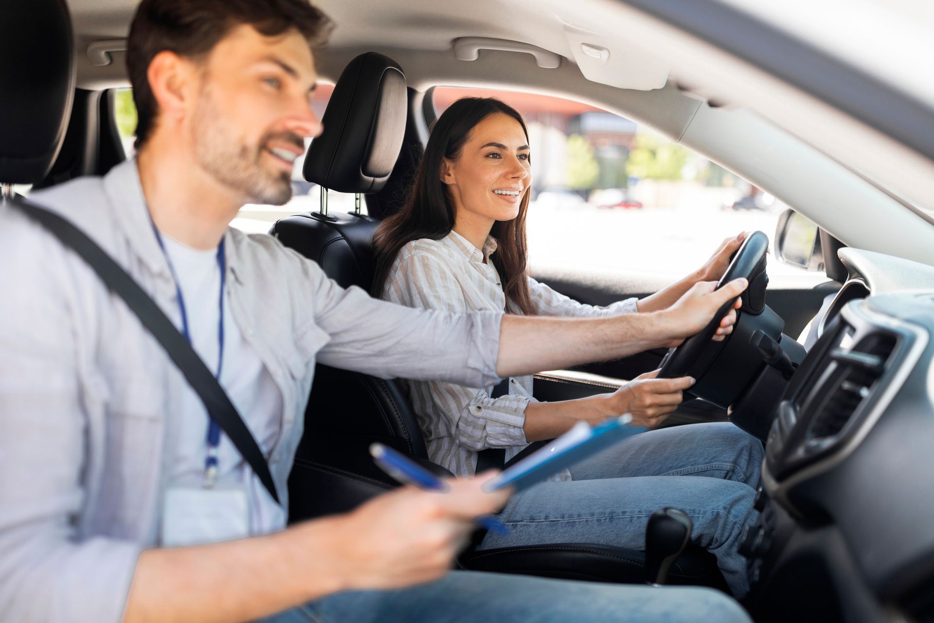 Smiling woman in a driving course with a male instructor beside her inside the car.
