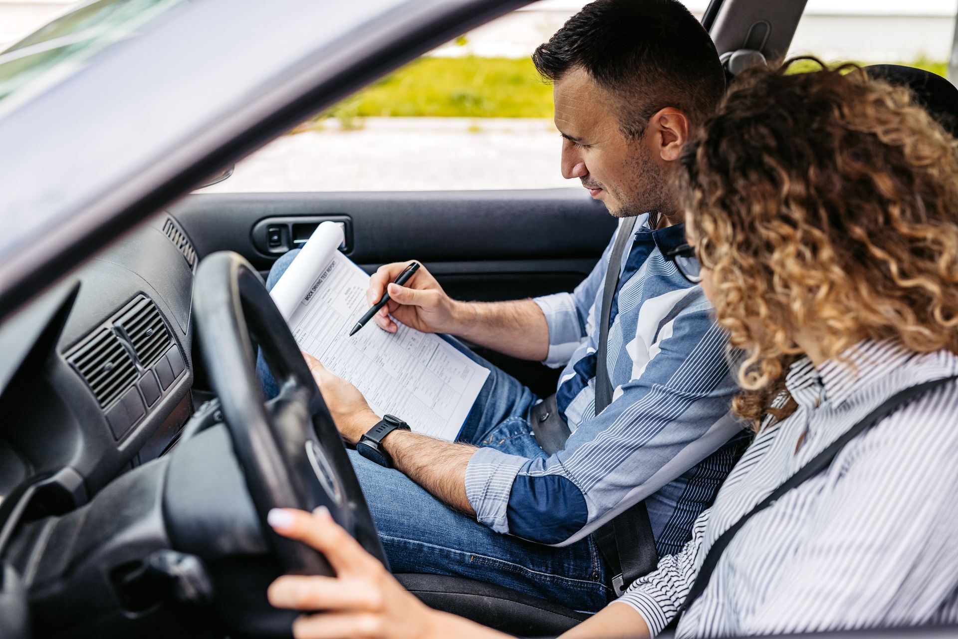 Driving instructor grading his female student on a driving test.