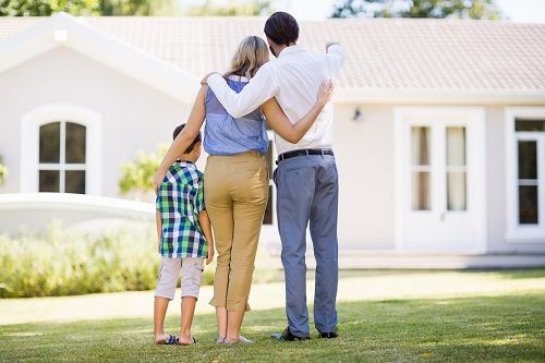 family of three sitting outside of home