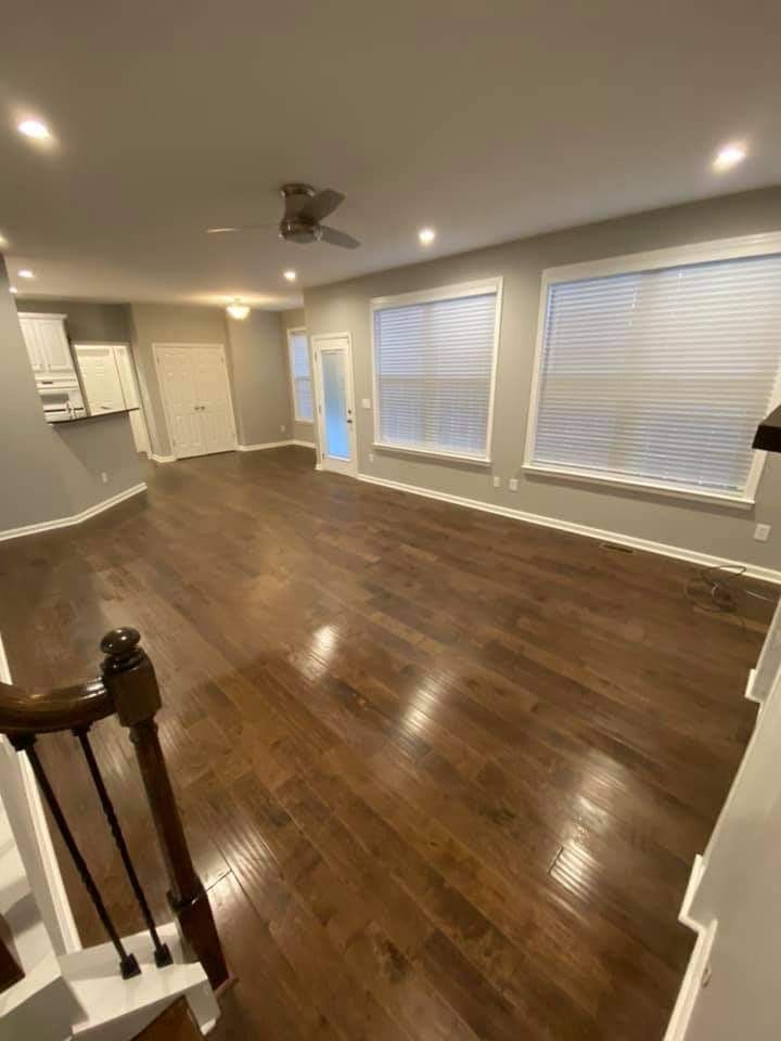 Hardwood floored living room with large windows, recessed lighting, and a doorway.