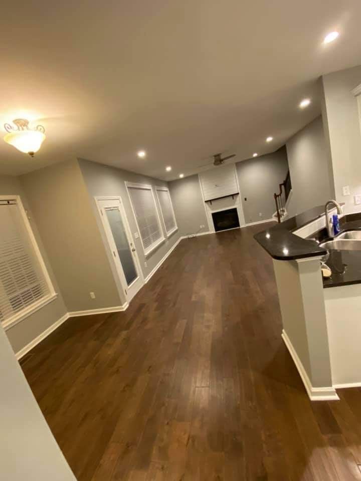 Spacious living room with dark wood floors, gray walls, recessed lighting, fireplace, and bar area.
