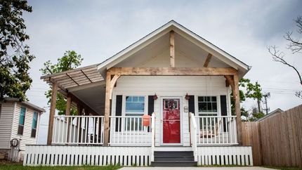 A small white house with a red door and porch.