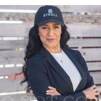 A woman in a suit and hat is standing in front of a wooden fence.