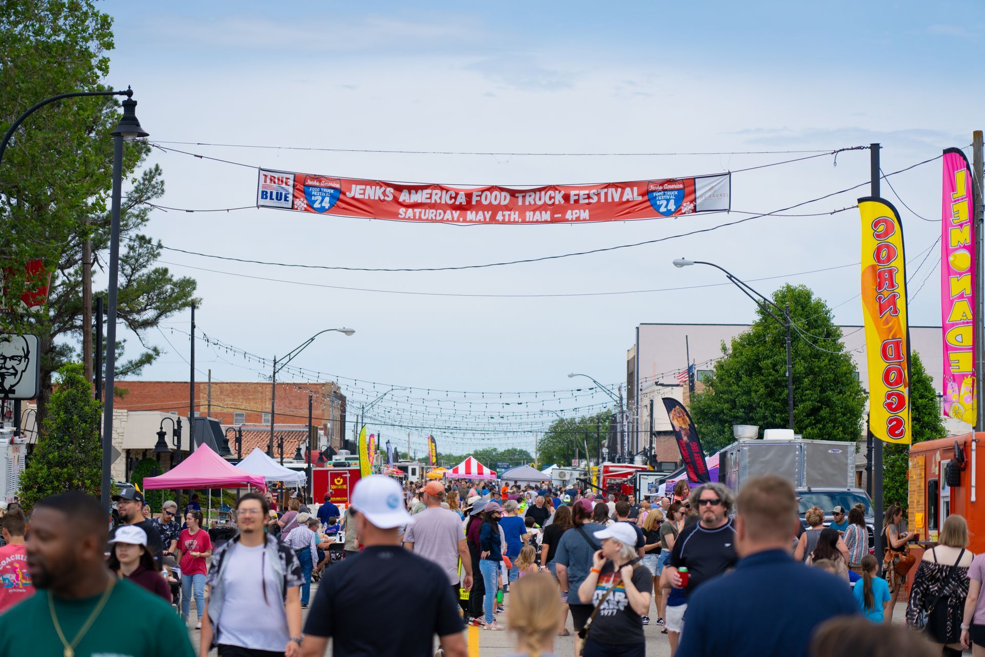 A long exposure photo of a street at night with lots of lights hanging from the trees.