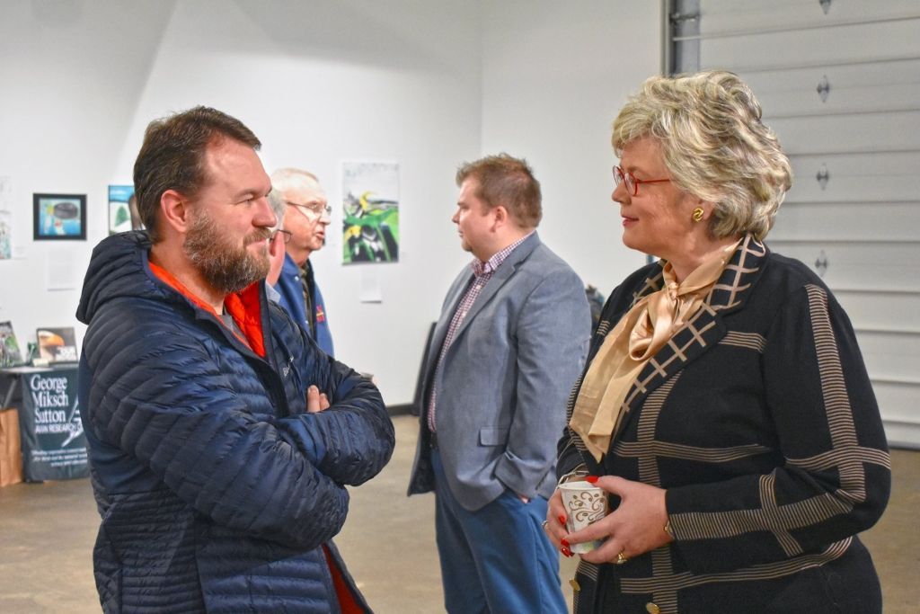 A group of people are standing in a room talking to each other.