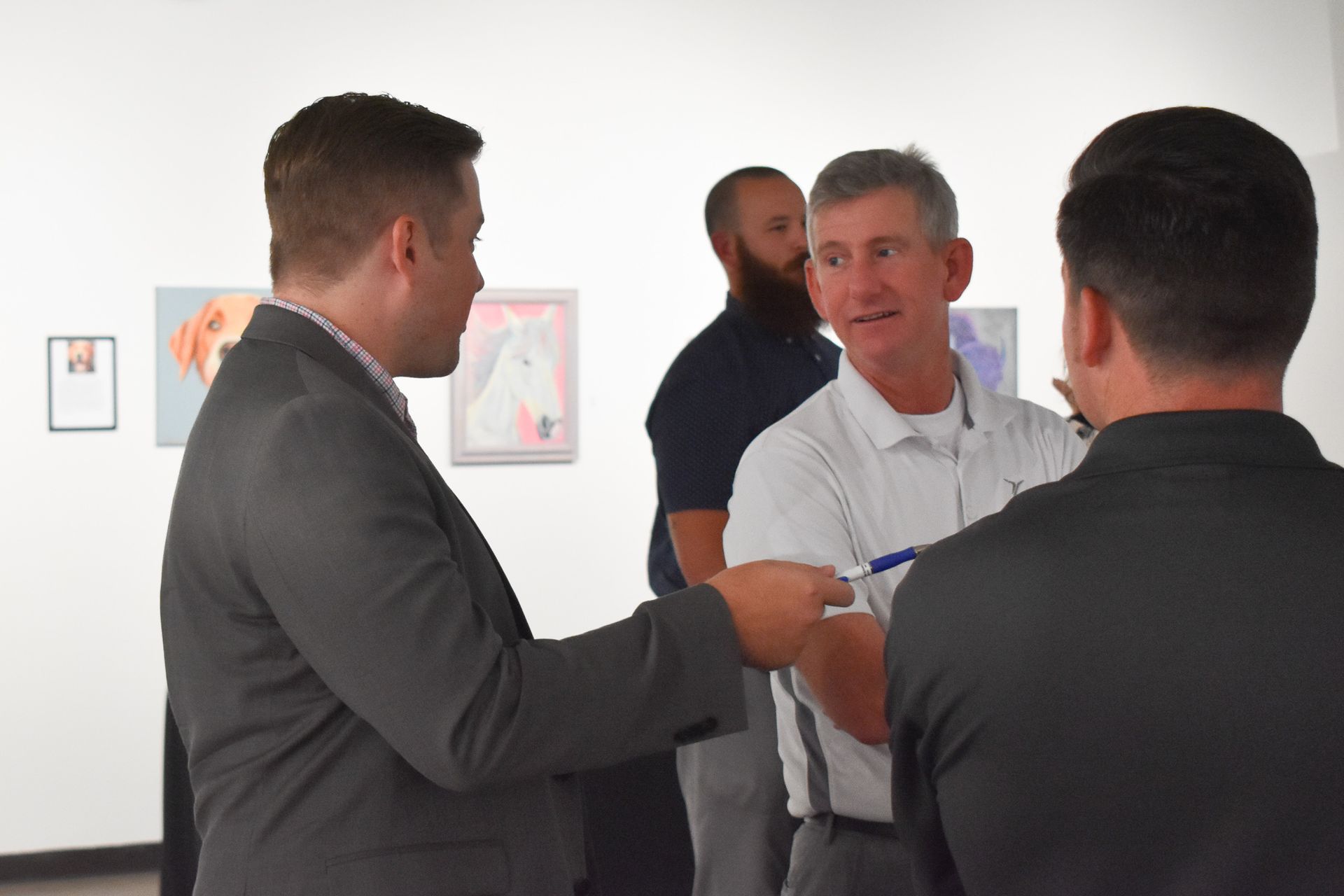 A group of men are standing in a room talking to each other.