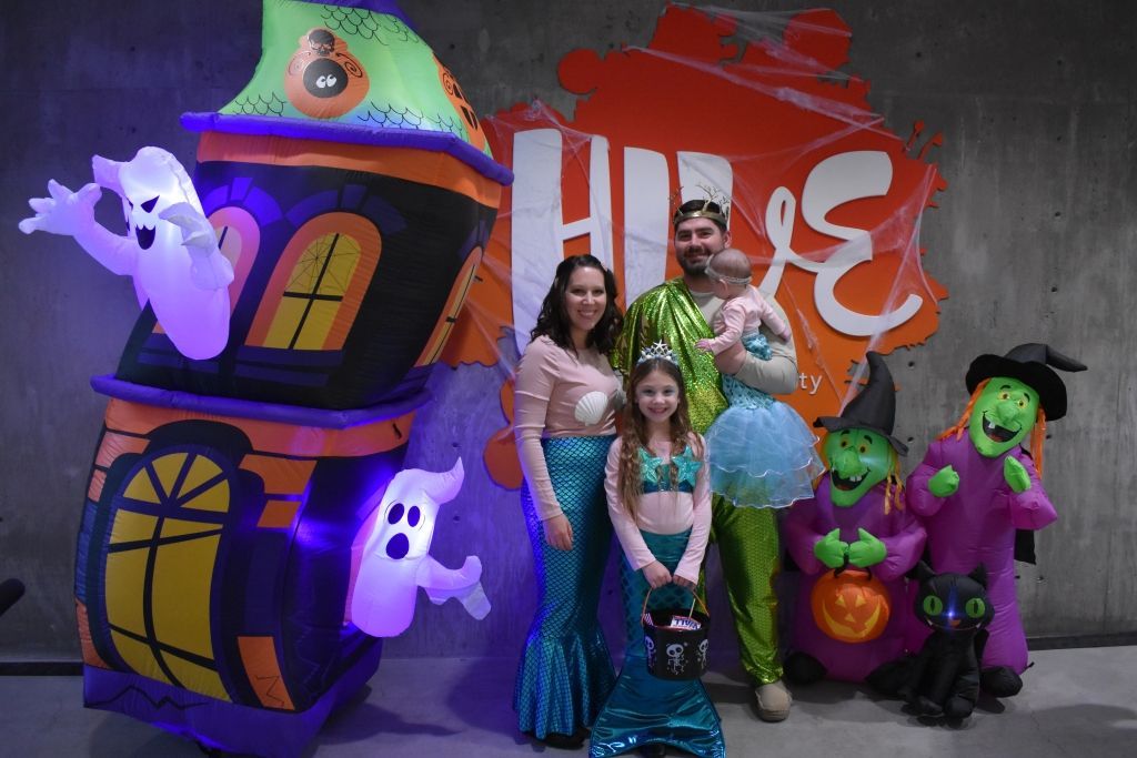 A family is posing for a picture in front of a halloween decoration.