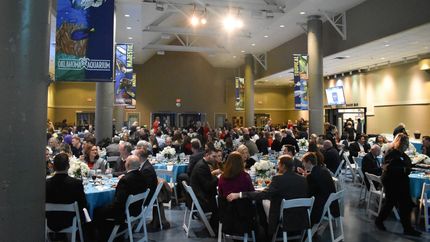 A large group of people are sitting at tables in a large room.
