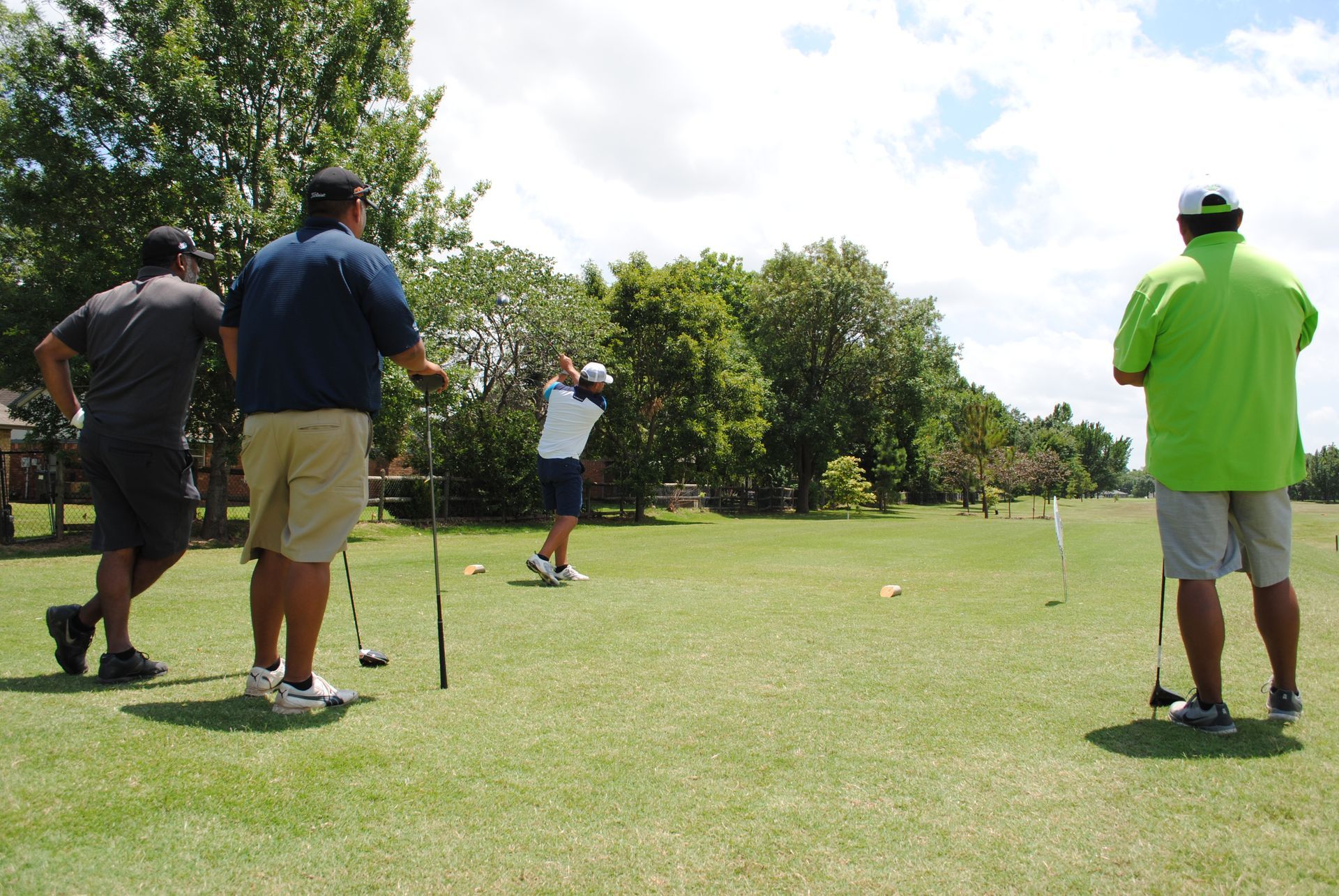 A group of men are playing golf on a lush green field