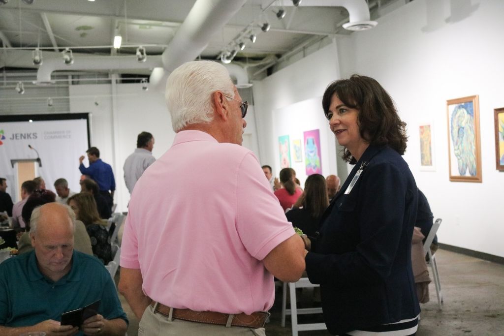 A man in a pink shirt is talking to a woman in a black jacket