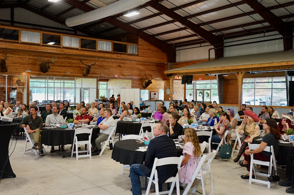 A large group of people are sitting at tables in a large room.