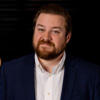 A man with a beard is wearing a blue suit and white shirt.