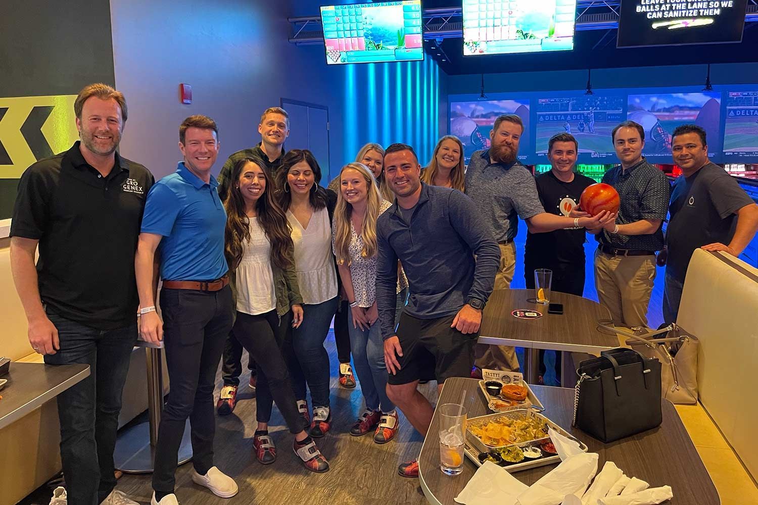 A group of people are posing for a picture in a bowling alley.