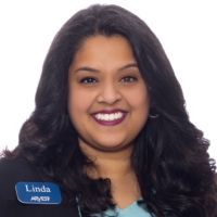 A woman with long hair is smiling and wearing a name tag.